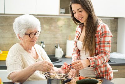 woman helping senior woman to cook
