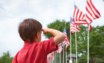Boy salutes flags at Memorial Day display in a small town