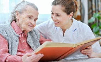 caregiver reading a book together with senior woman