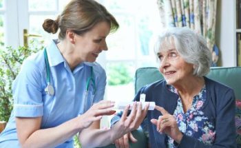 nurse giving medication to senior woman