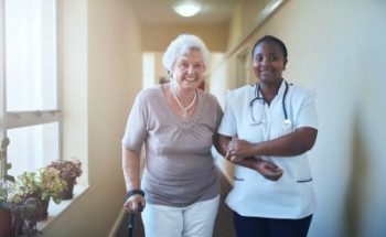 caregiver and senior woman walking in the hallway