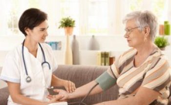 nurse checking blood pressure of senior woman